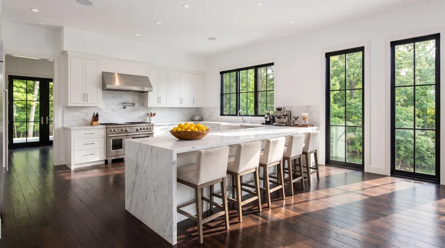 Chef's kitchen with a white marble waterfall island, counter seating and a stainless range